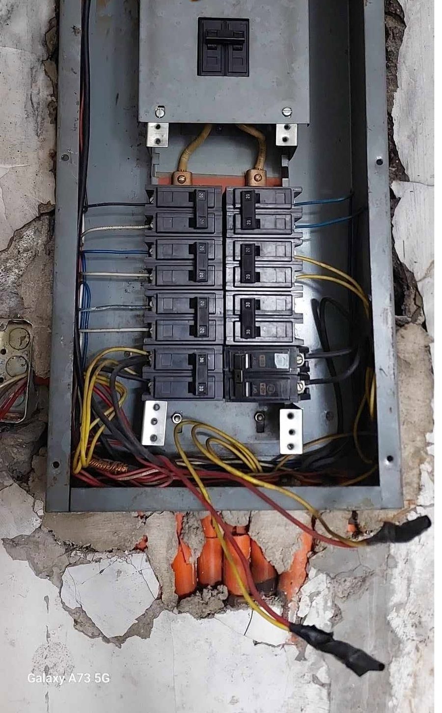 Old corroded electrical panel exposed in a broken concrete wall